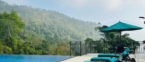 A poolside area with lounge chairs and a view of a mountainous landscape.