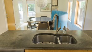 A kitchen with a double sink, a modern faucet, and a dining area with a round table and chairs.