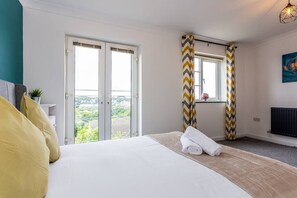 Relax in comfort with a large bed and sliding glass door leading to a balcony with a view of the surrounding area.