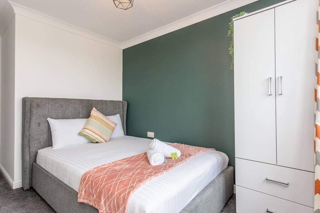 Une chambre à coucher avec un lit, une armoire et un mur d’accent de couleur verte.