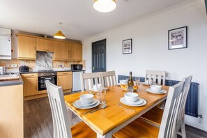 Enjoy meals in this well-equipped kitchen and dining area, featuring a dining table and comfortable seating.