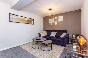 Relax in this stylish living room with a sofa, coffee table, and lamp, surrounded by artwork and a large mirror.