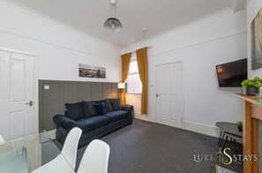 A modern living room with a sofa, a glass table, and a TV.