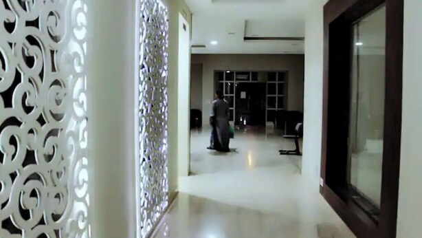 A hallway with a decorative white wall on the left, a large window on the right, and a person walking in the distance. - Explore Rajasthan's rich cultural heritage in NCR (Neemrana)