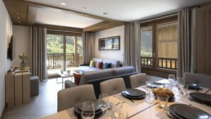 A spacious room with a dining area, a sofa, and a balcony with a view of the countryside.