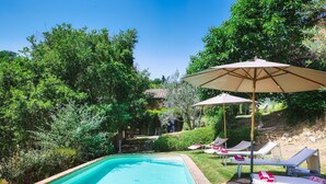 A swimming pool with lounge chairs and umbrellas, surrounded by lush greenery. - Casa di Pan 6, Emma Villas (Panicale)