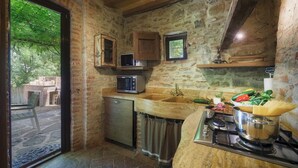 A rustic kitchen with stone walls, a built-in oven, a sink, and a stove. - Casa di Pan 6, Emma Villas (Panicale)