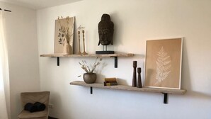 Une chambre à coucher comprenant un lit, une chaise et deux étagères fixées au mur, ornées d’objets décoratifs.