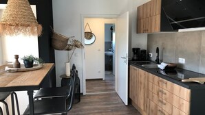 Une cuisine moderne avec des meubles en bois, un plan de travail noir et un coin repas comprenant une table en bois et des chaises noires.
