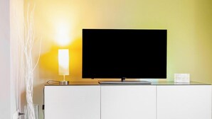 A television on a white cabinet with a wall-mounted lamp beside it. - VALPOLICELLA APARTMENTS: OLIVE TREE RESIDENCE (Valgatara)