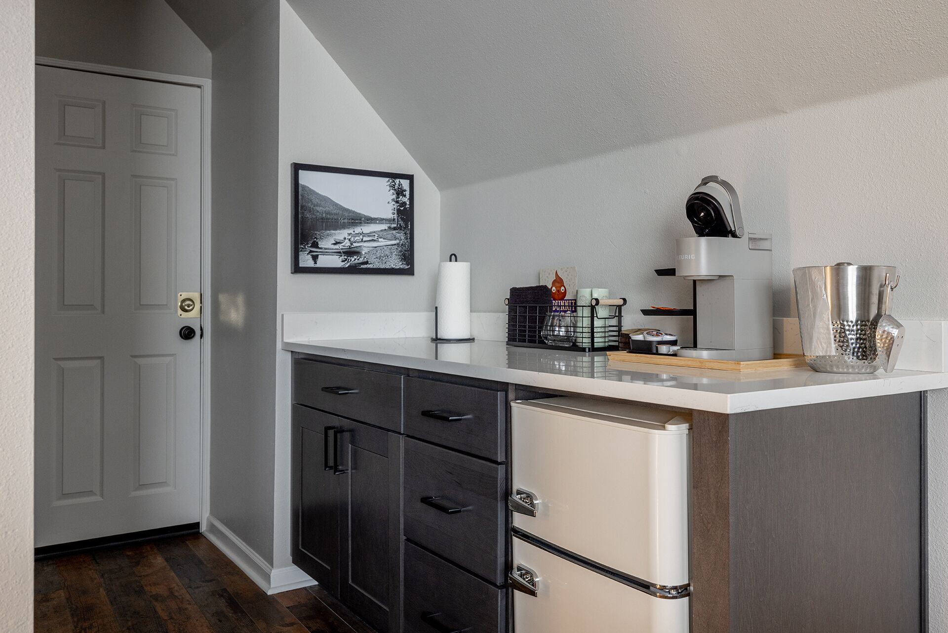 A compact kitchen with a refrigerator, a coffee machine, and a small countertop.