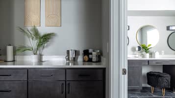 A modern bathroom with dark wood cabinets, a white countertop, and a mirror with a gold frame.