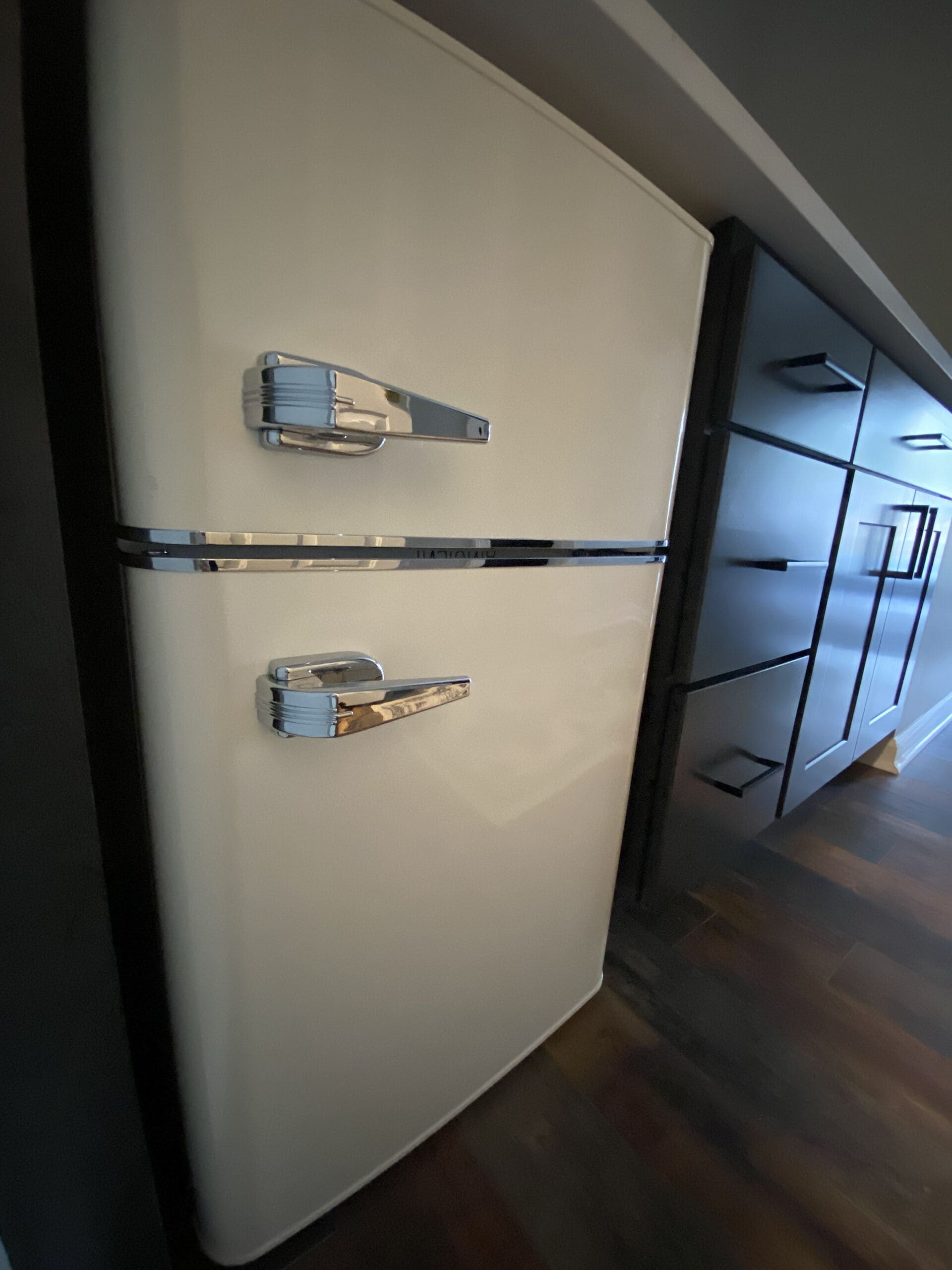 A modern kitchen with a white refrigerator, double doors, and a stainless steel handle.