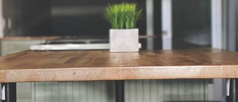 Cocina con encimera de madera, dos taburetes de metal y una planta en maceta.