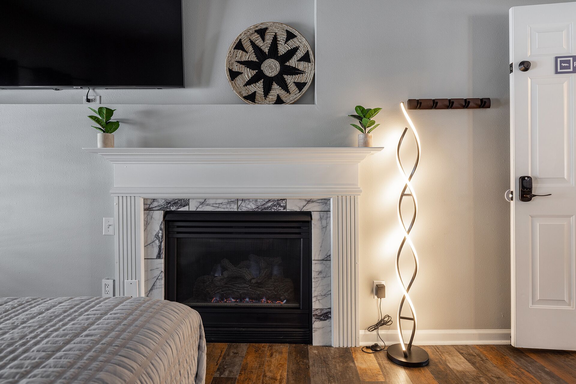 A modern living room with a fireplace, a dartboard, and a floor lamp.