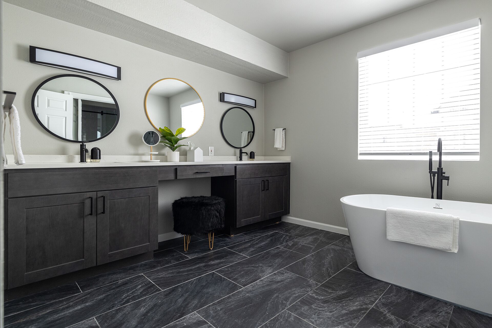 A modern bathroom with dark wood cabinets, a white vanity, and a freestanding bathtub.