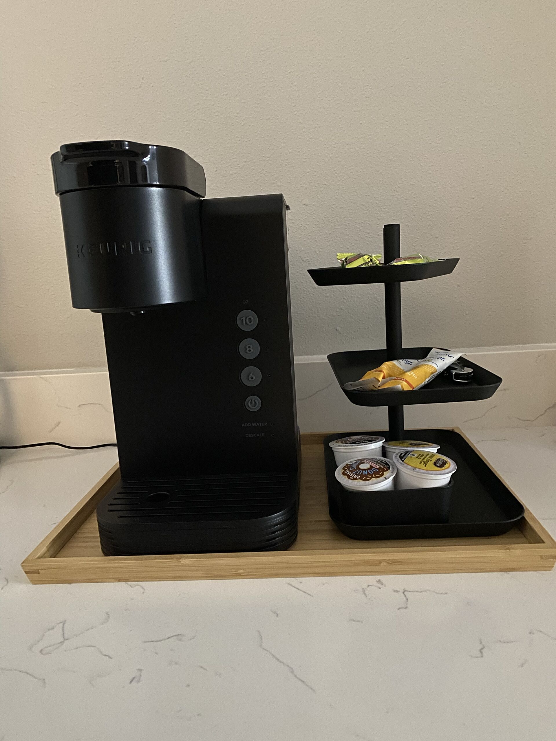 A Keurig coffee maker with a three-tiered serving tray beside it.