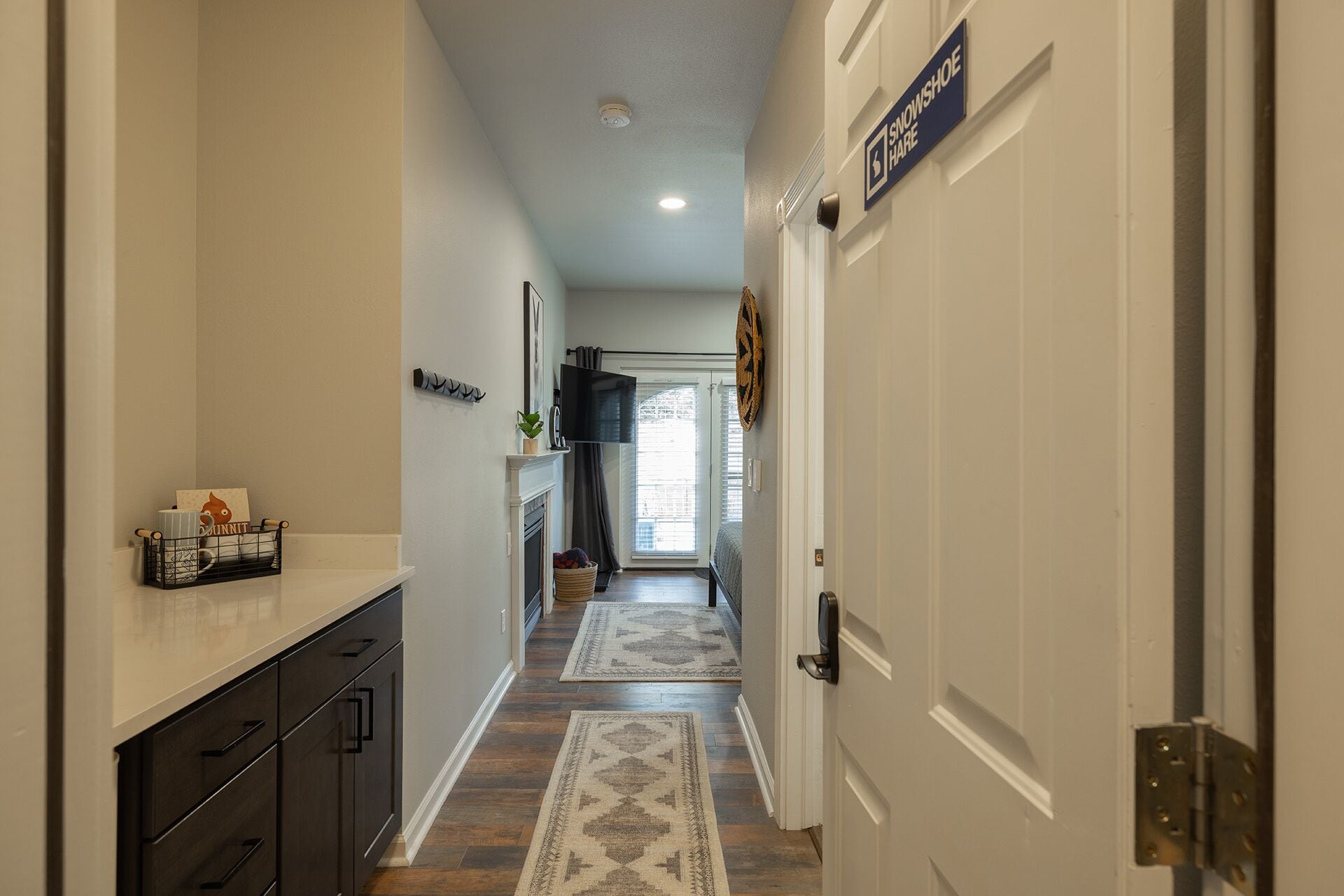 A hallway with a fireplace, a sign for a shoe store, and a door with a handle.
