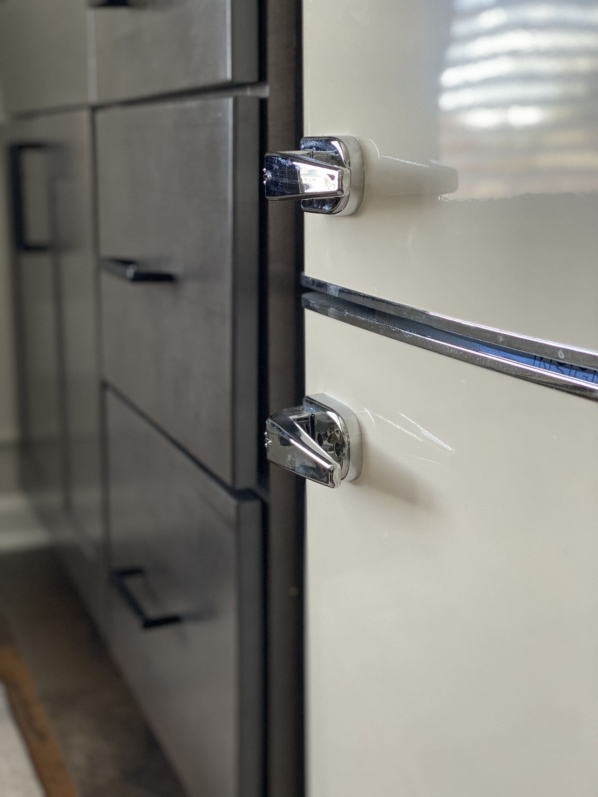 A close-up of a metallic handle on a white cabinet with a reflective surface.