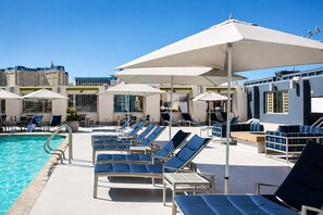 Een zwembadterras met ligbedden, parasols en een helderblauw zwembad.