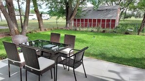 An outdoor patio with a glass-top table and wicker chairs.