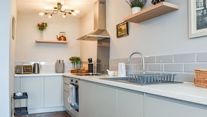 Een moderne keuken met een centraal eiland, een ingebouwde oven en een roestvrijstalen afzuigkap.