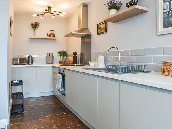 A modern kitchen with a central island, a built-in oven, and a stainless steel range hood.