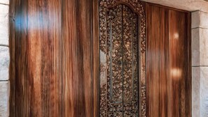 A wooden door with intricate carvings and a metal panel.