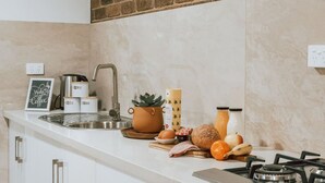 A kitchen with a sink, stove, and various kitchen items like a coffee maker, jars, and a potted plant.