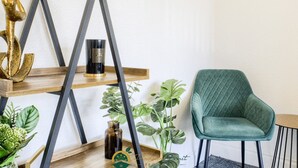 A modern interior with a green upholstered chair, a wooden shelf with decorative items, and a logo for Passion Fruit Properties. - 52NRC Unli Wi-fi 3 Bedroom House (Coventry)