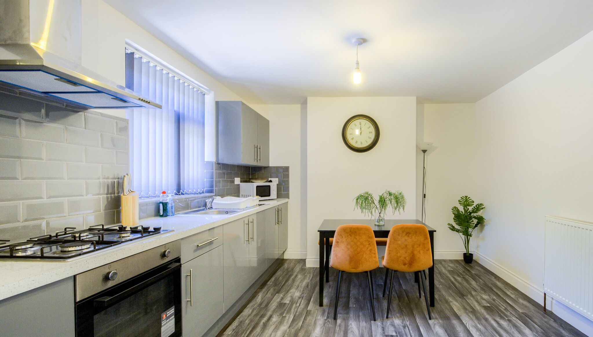 A modern kitchen with a gas stove, microwave, and a dining area with two chairs and a table.
