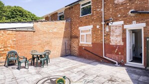 A brick building with a patio area, outdoor seating, and a door leading to an interior space. - 52NRC Unli Wi-fi 3 Bedroom House (Coventry)