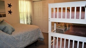 Een slaapkamer met een bed, een ledikant, een deur en een raam met gordijnen.