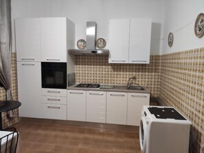 A compact kitchen with white cabinets, a built-in oven, a gas stove, and a sink. - Sunny Seaside Escape in San Pier Marina (San Pier Niceto)