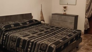 Une chambre à coucher avec un lit, une commode, un miroir et un tapis à motifs.