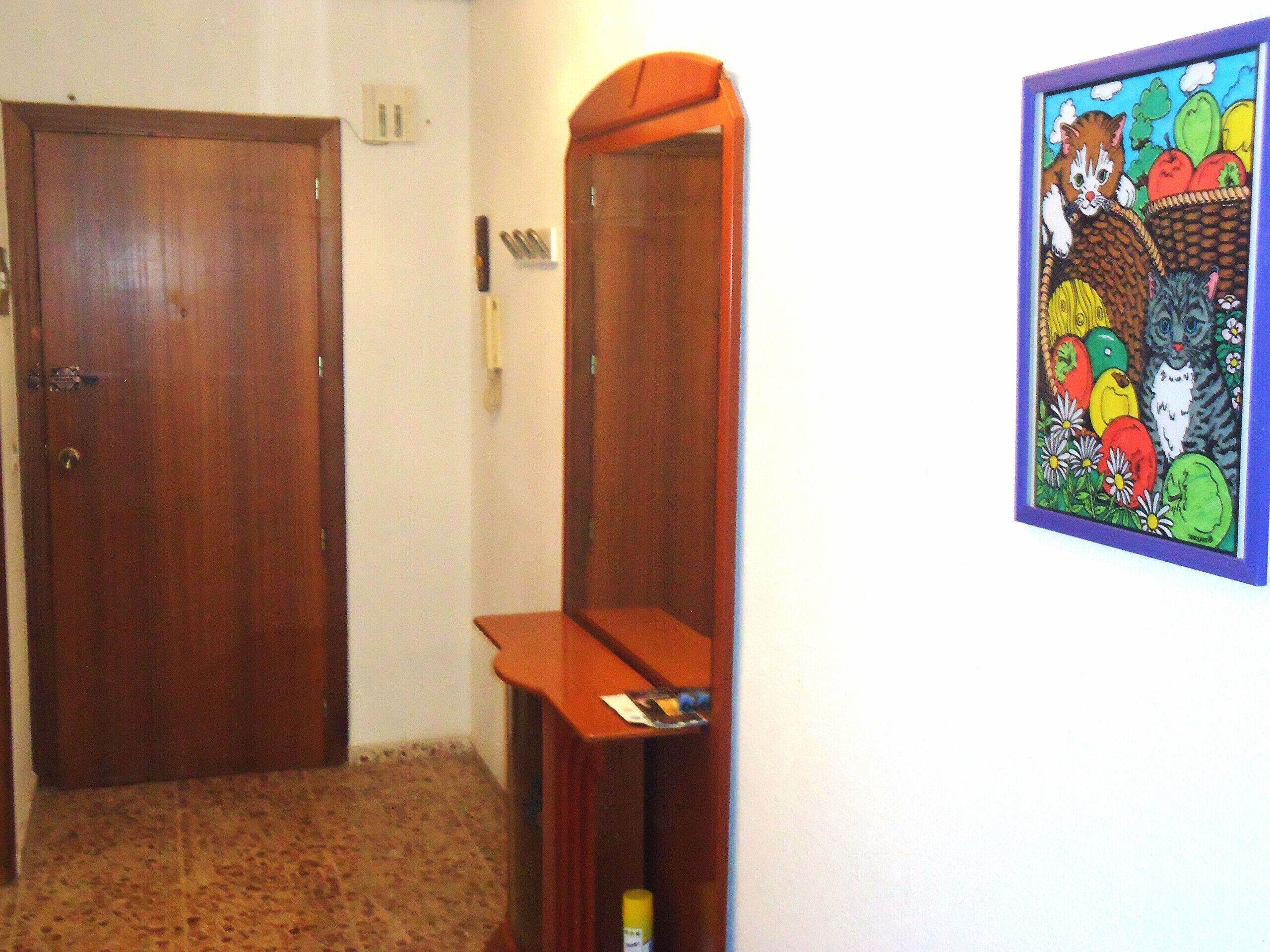 Ein Korridor mit einer Holztür, einem Spiegel und einem gerahmten Gemälde an der Wand.