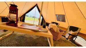 A tent interior with a table, a lantern, a basket, and a chair. - Cozy Bell Tent Retreat at Lake Texoma (Kingston)