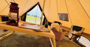 Ein Zeltinnenraum mit Tisch, Laterne, Korb und Stuhl.
