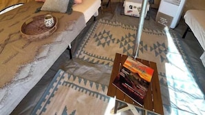 Une tente avec un lit, une petite table et une lampe, ainsi qu’un tapis.