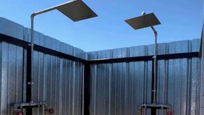 Une clôture métallique à laquelle sont fixées deux structures métalliques, chacune comportant une barre horizontale et un tube vertical.