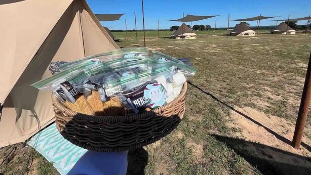 Un terrain de camping avec des tentes et un panier rempli de provisions.