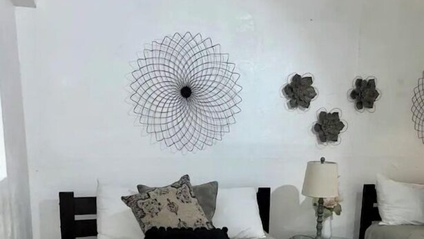 A bedroom with a large bed, a bedside table with a lamp, and decorative wall art.