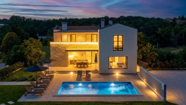 A modern two-story house with a swimming pool, outdoor seating, and a stone facade.