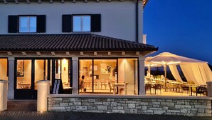 A building with a covered outdoor seating area, large windows, and a stone facade.