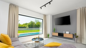 A modern living room with a large window, a flat-screen TV, and a minimalist design.