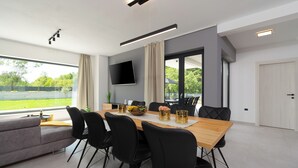 Un comedor moderno con una mesa de madera, sillas negras y un televisor de pantalla plana montado en la pared.