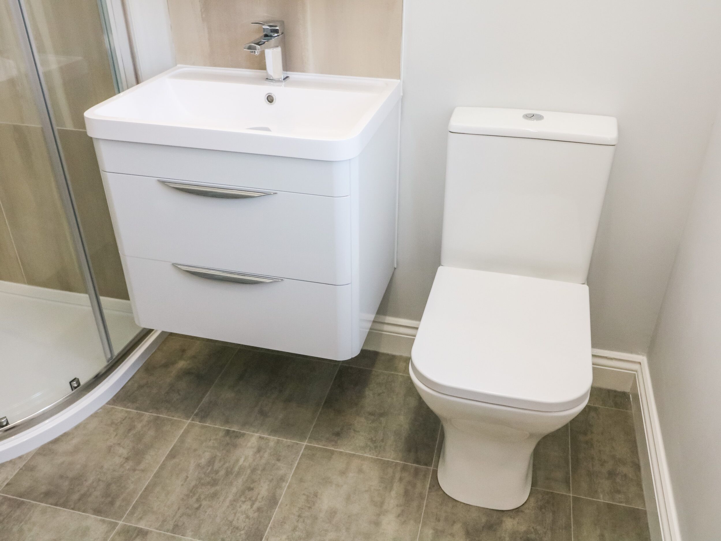 A bathroom with a white sink, a toilet, and a glass shower enclosure.