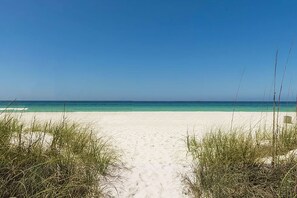 A beach with a clear path leading to the ocean, surrounded by grassy dunes.