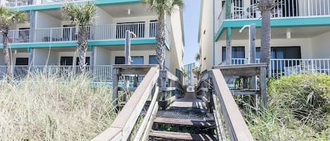Una escalera de madera que lleva a un edificio con varios balcones y vista al mar.