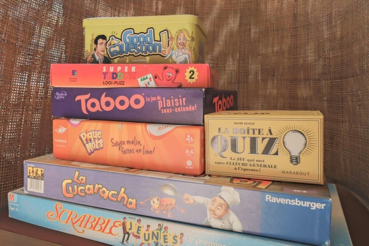 A stack of board games including Good Question!, Super Ted, Taboo, La Cucaracha, La Lote a Quiz, and Ravensburger.